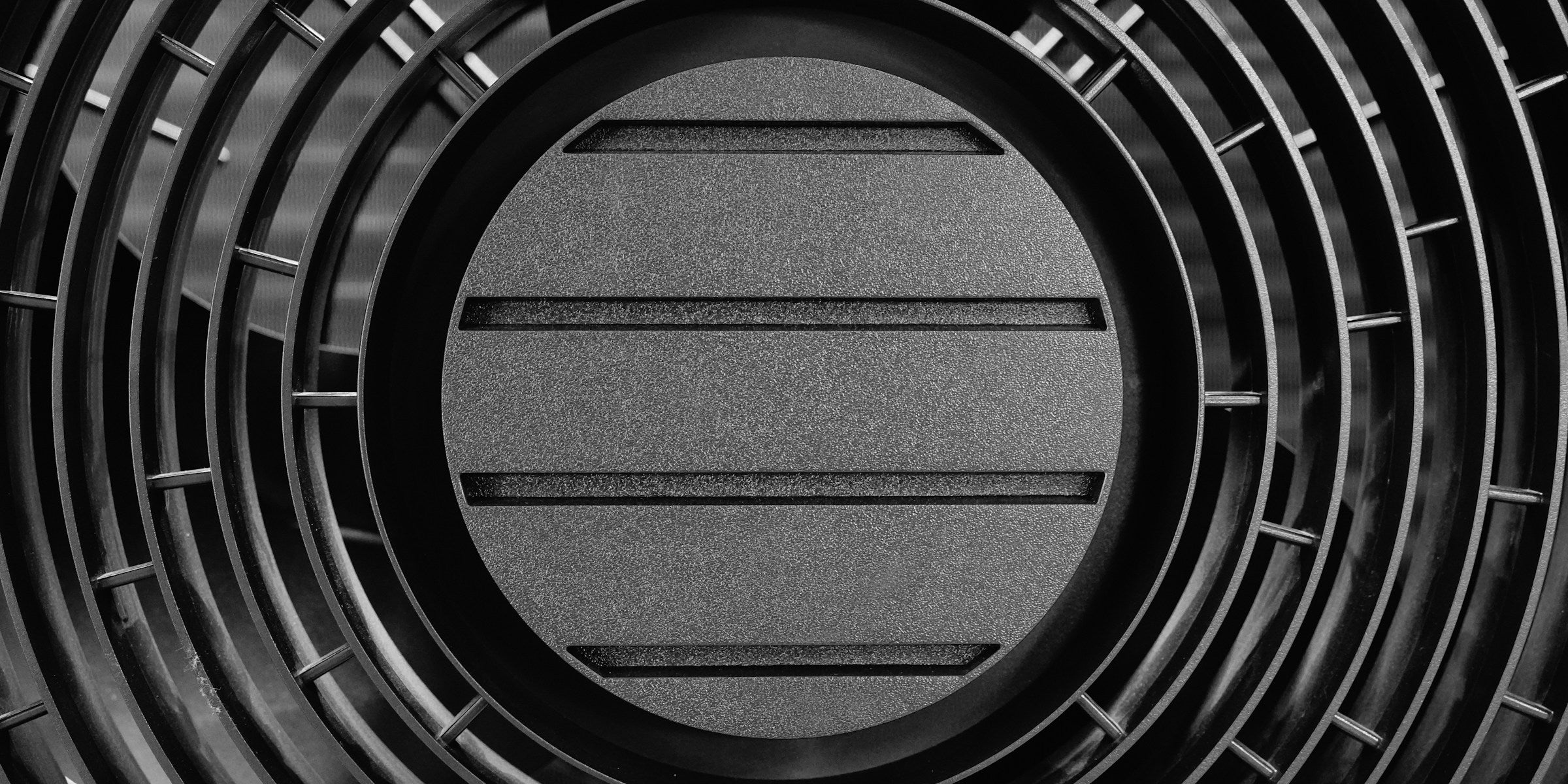 Close-up of a dark circular ventilation grille with horizontal slats