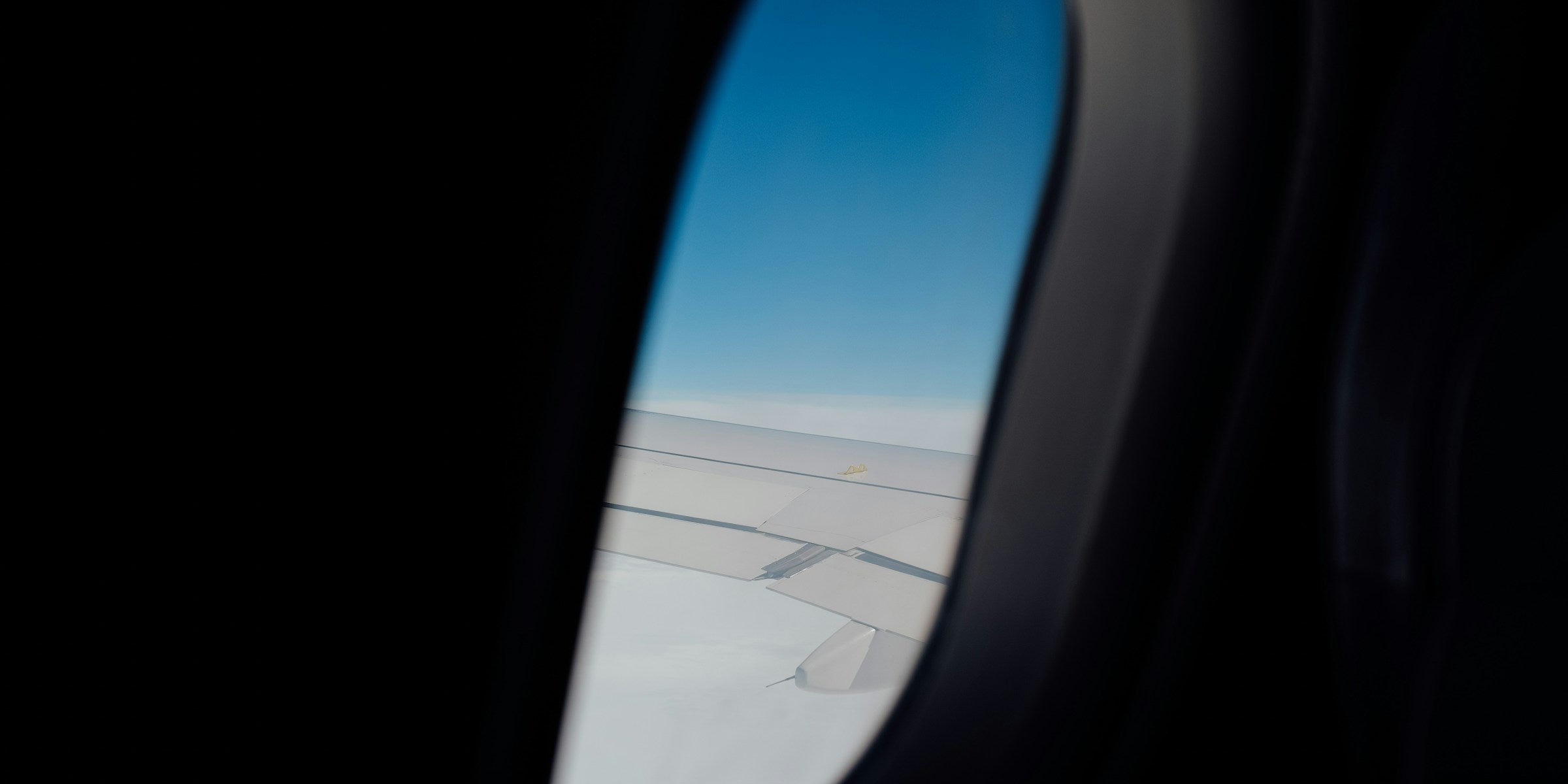 View of pale clouds and open sky through an aircraft window in soft daylight
