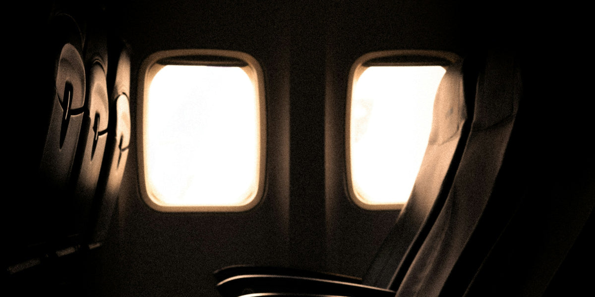 Dim airplane cabin interior with rows of empty seats lit by soft window light