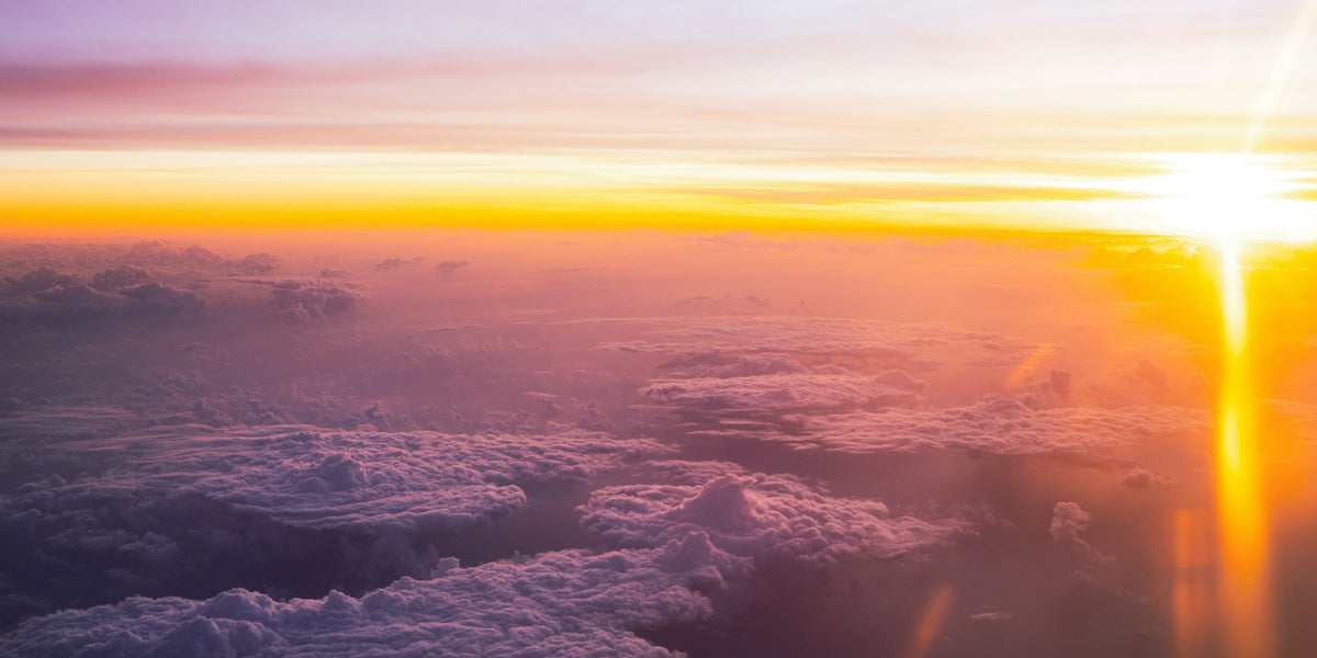 Layered clouds under a pale sky seen from an aircraft window at sunrise