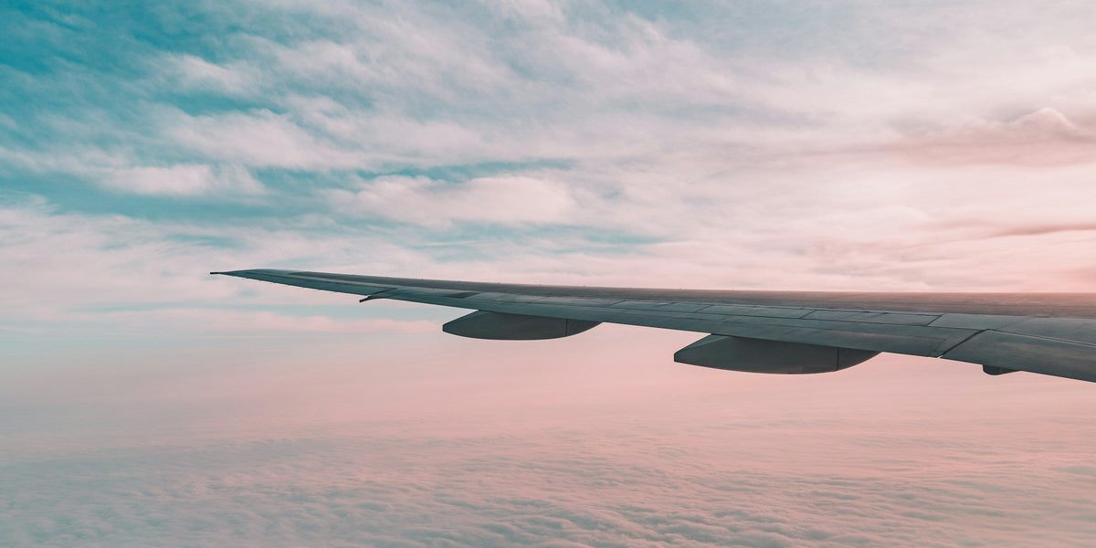 Airplane wing above a soft layer of pale clouds in muted grey light