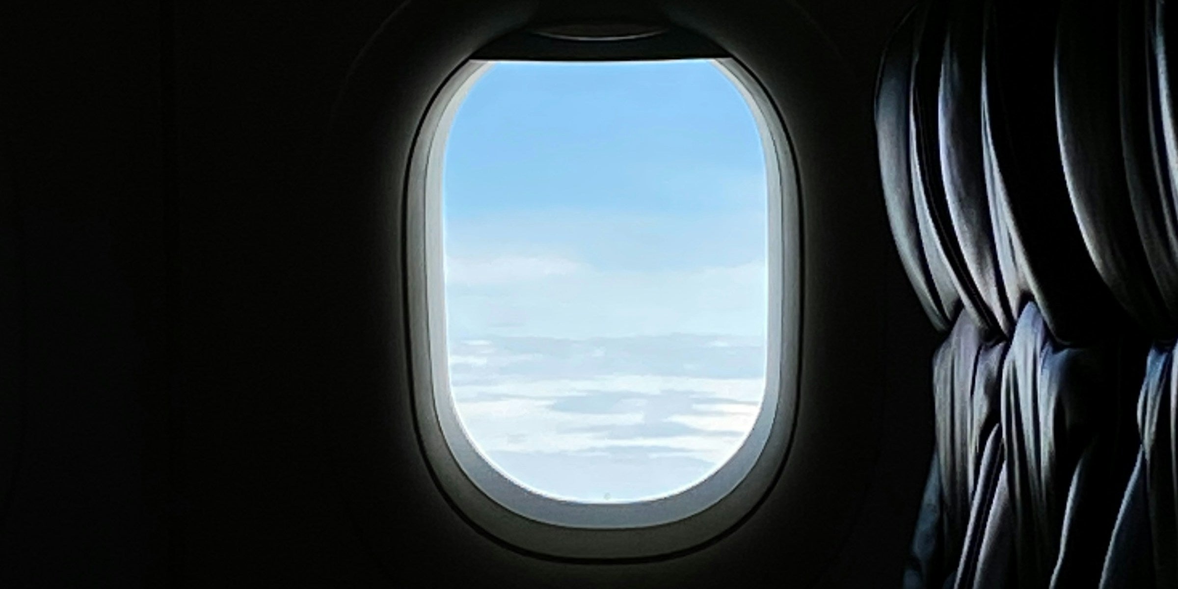 View of open sky through an airplane window in muted low light