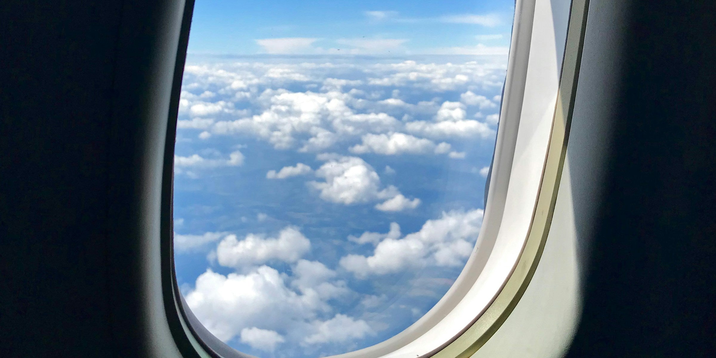 View of bright clouds through an aircraft cabin window in soft daylight