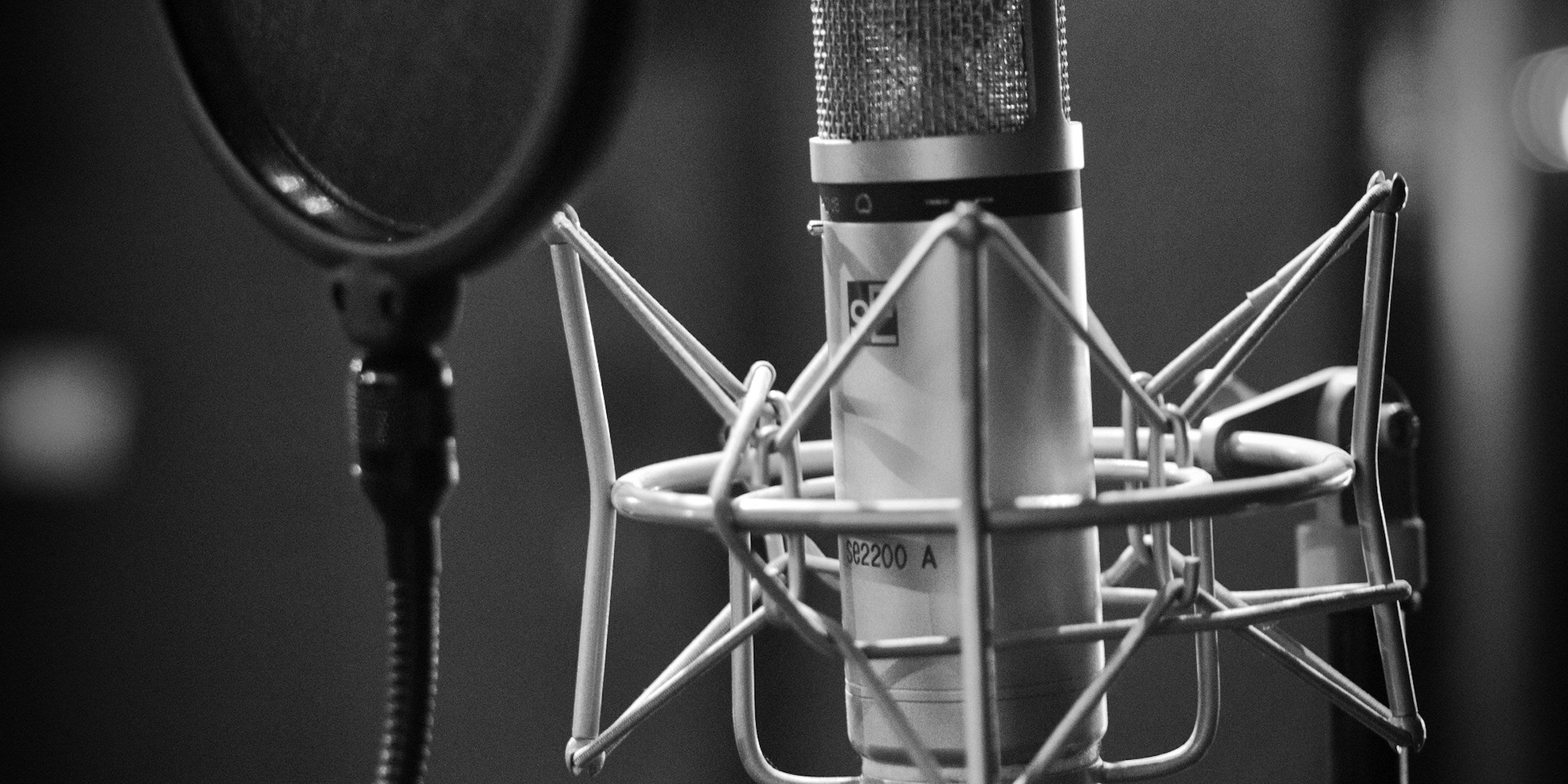 Condenser microphone and pop filter in a recording studio, shown in grayscale